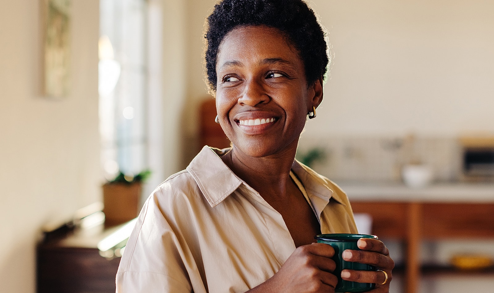 Smiling Lancaster orthopedic surgery woman holding a cup in bright kitchen.